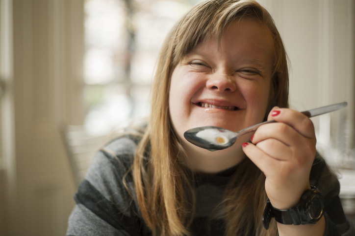 Girl with Down Syndrome holding a spoon - eating