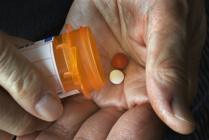 Senior Hand Pouring Pill Medicine from Prescription Bottle in Palm