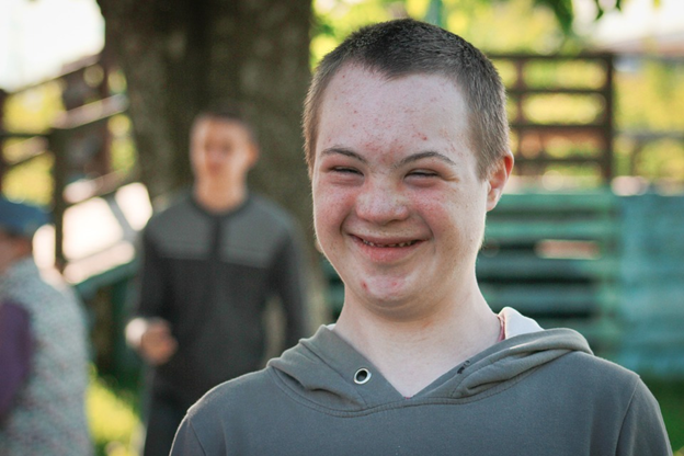 Boy with an intellectual and developmental disabolity in a grey hoodie smiling