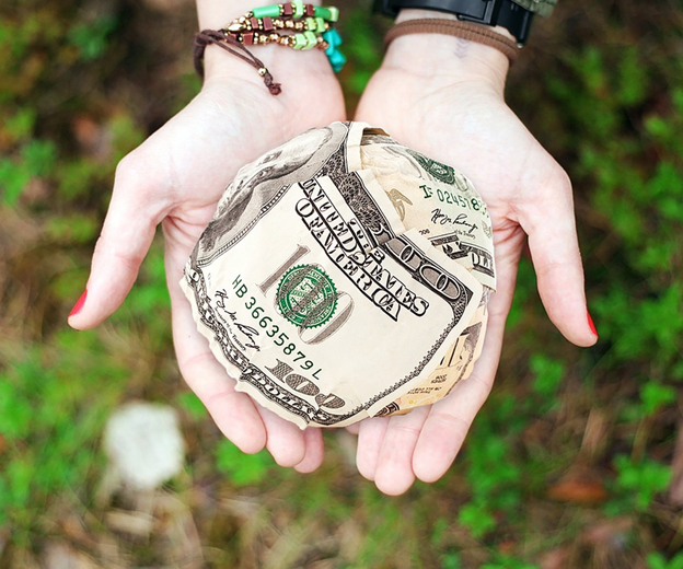 A ball of cash sitting in the middle of two palms together