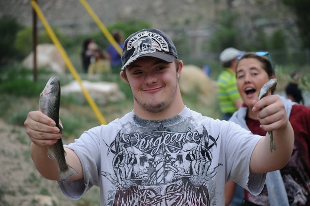 Disabled man holding his fishing catch showing his victory