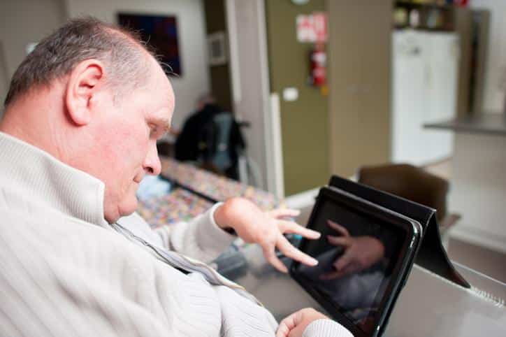 Mature aged man with a disability operating touchscreen computer