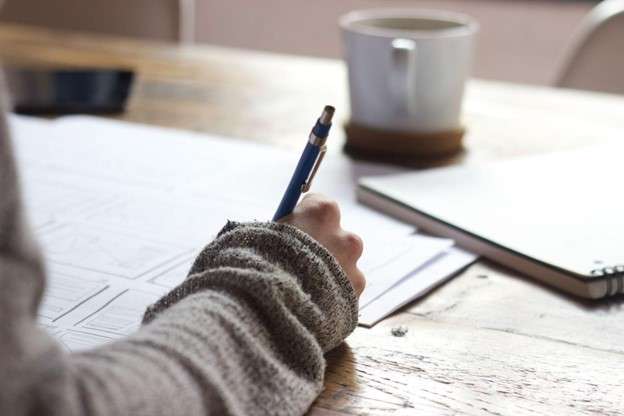 hand on desk, filling out paperwork