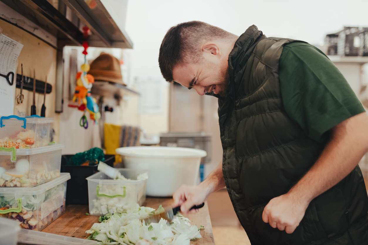 Man with down syndrome working in kitchen in zoo, prepairing food for animals.Concept of integration people with disabilities into society. Man with down syndrome working in kitchen in a zoo,