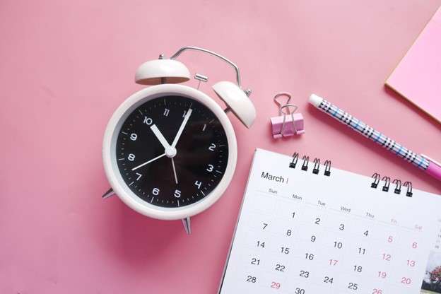 White clock and calendar on a baby pink background