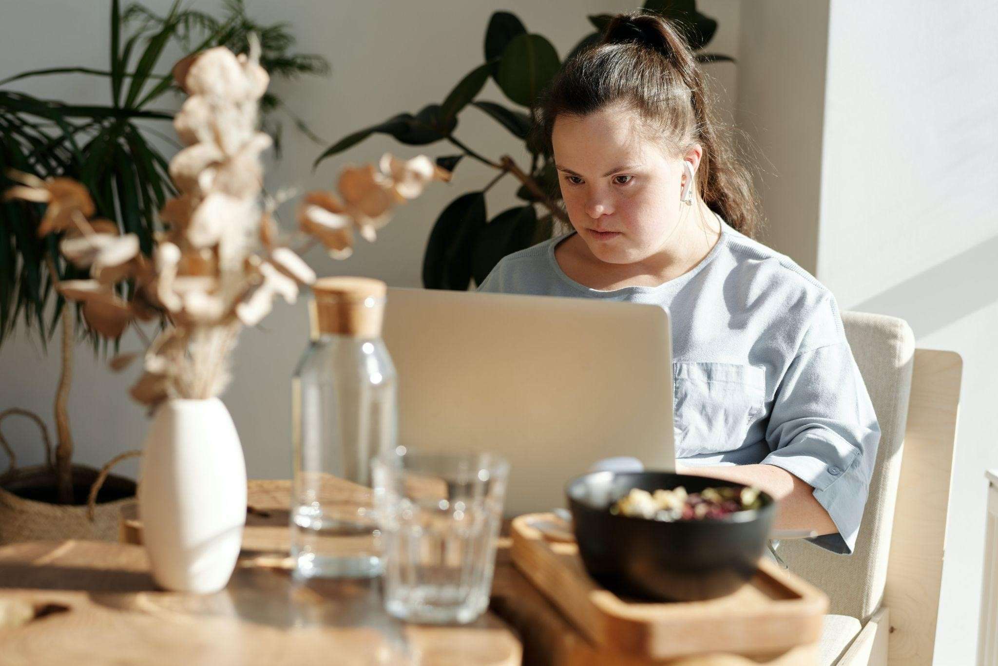Young Woman with down syndrome is sitting in front of a computer.