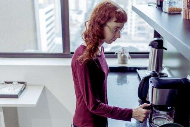 Woman preparing coffee in her kitchen as part of a morning routine at home